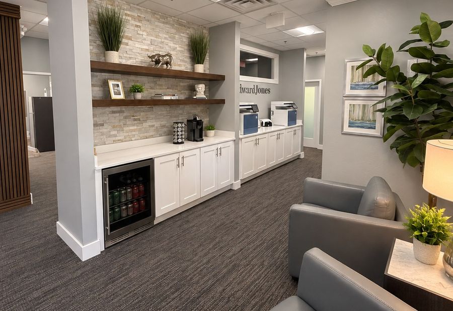 Finished commercial office build-out by Harrison Building Co — stone-faced coffee bar with floating walnut shelves, white shaker cabinetry, quartz counter, and a carpeted client lounge